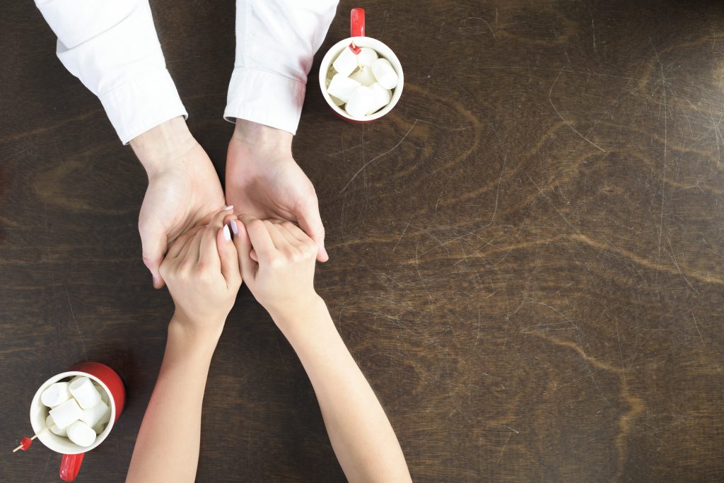 Two people holding hands over a coffee
