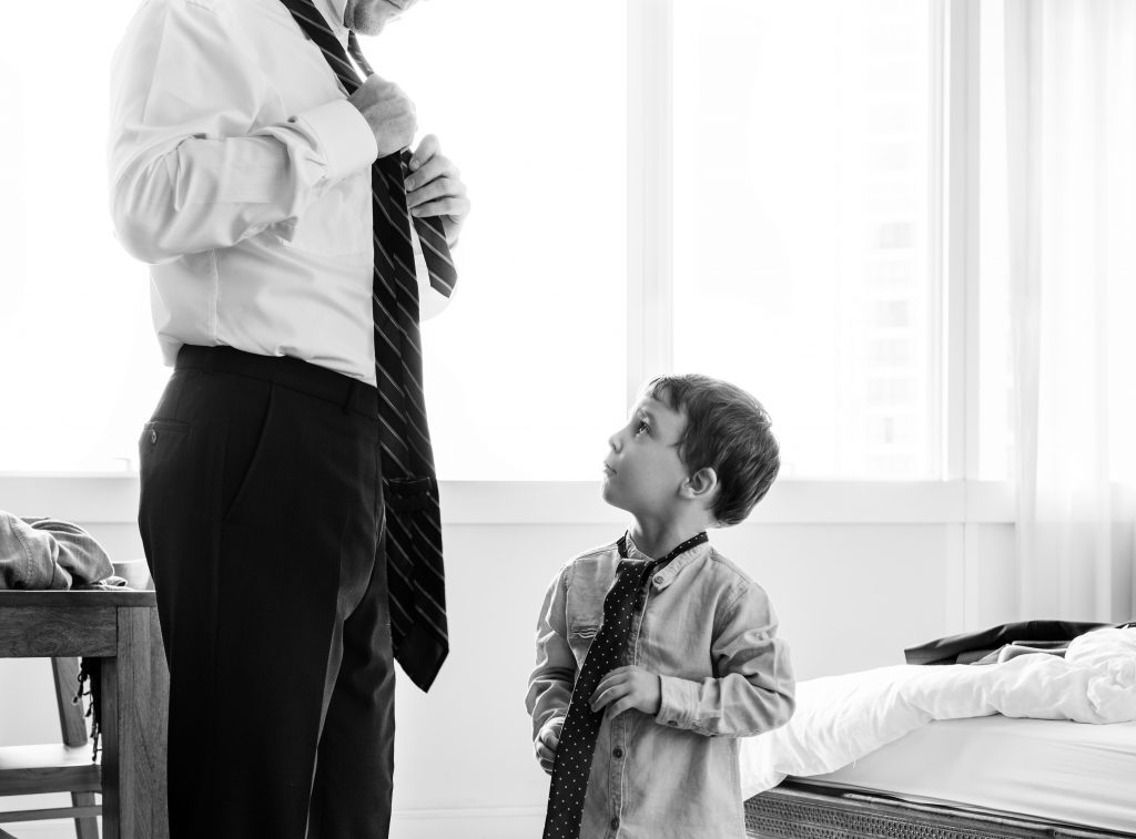 Father teaching son how to tie a tie