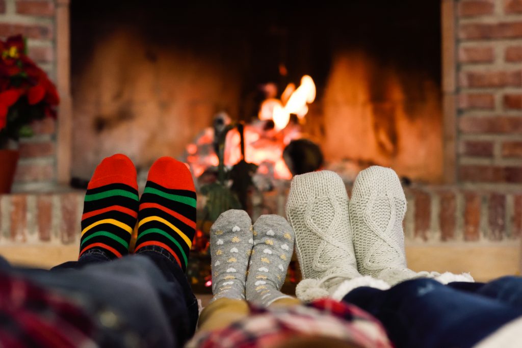 Feet in Christmas socks near fireplace