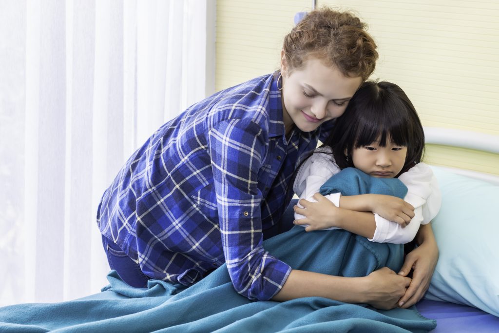 Mother reassuring and discussing her daughter. Patient girl sad on bedroom hospital.