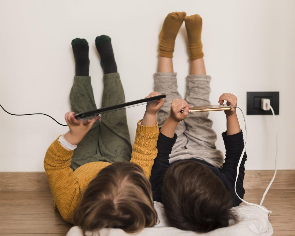 Two foster children playing on their devices - Fostering in the midlands